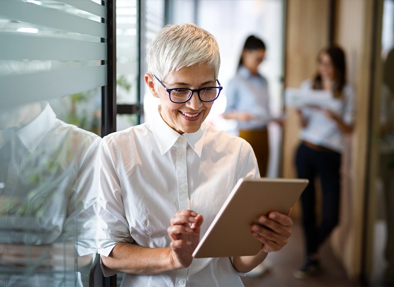 Eine Frau steht im Büro und nutzt ihr Tablet zur Prozessoptimierung